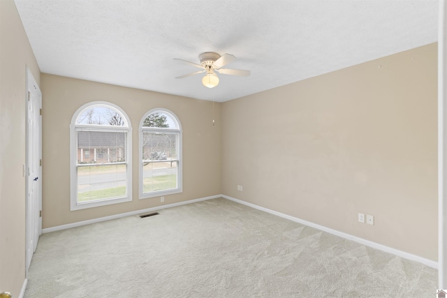 carpeted empty room with ceiling fan and a textured ceiling