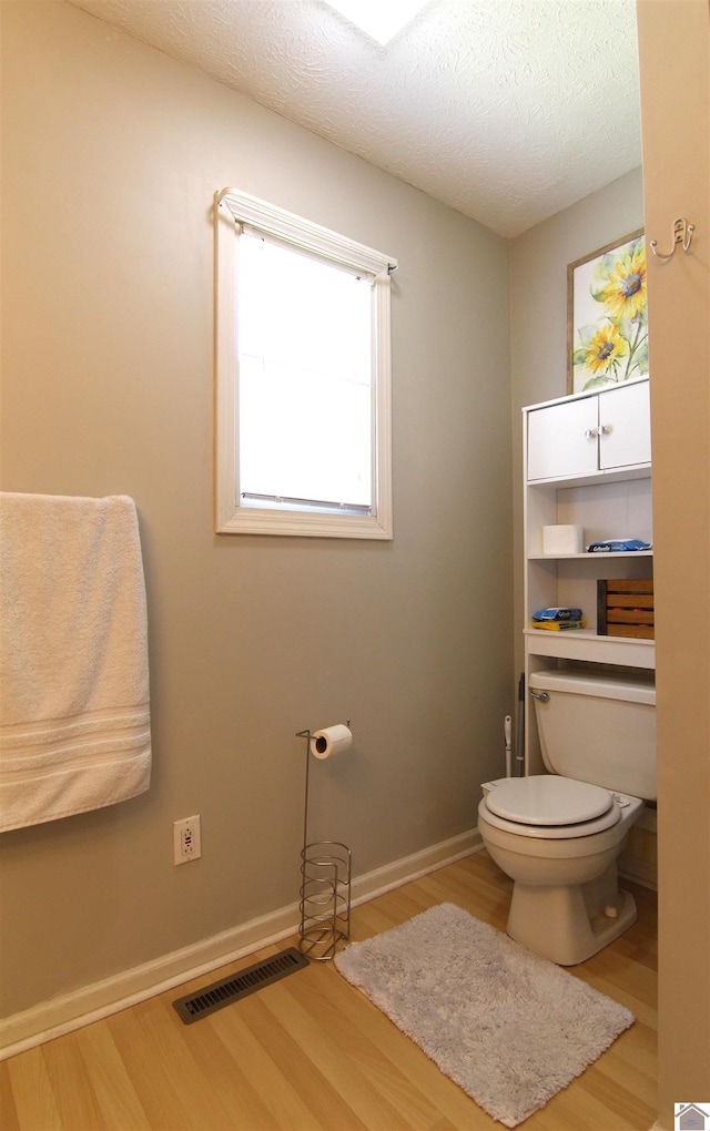 bathroom with hardwood / wood-style floors, a textured ceiling, and toilet