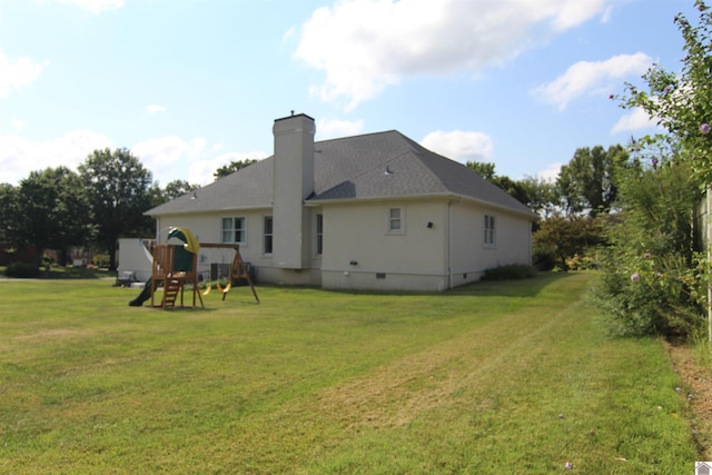 rear view of house with a playground and a yard