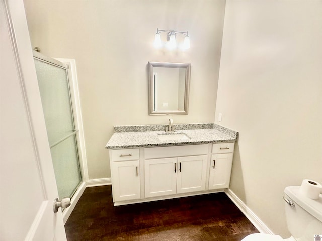 bathroom with toilet, vanity, walk in shower, and wood-type flooring