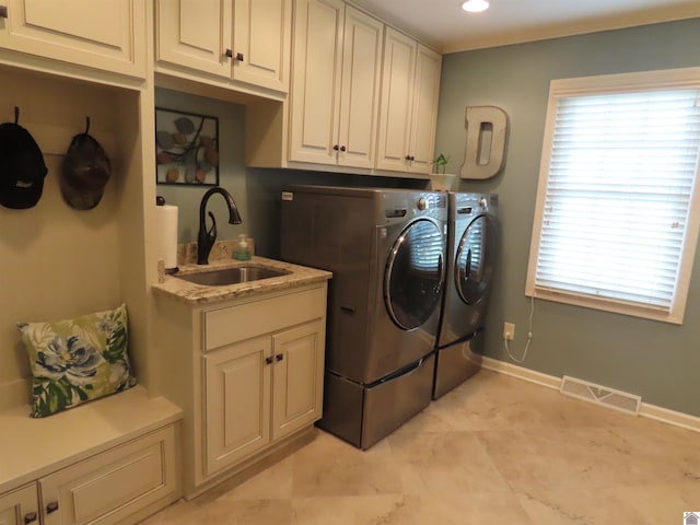 laundry area featuring washing machine and clothes dryer, cabinets, light tile patterned floors, and sink