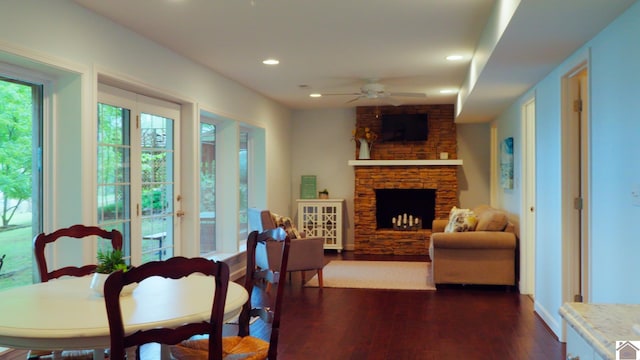 living room featuring brick wall, a stone fireplace, dark wood-type flooring, and ceiling fan