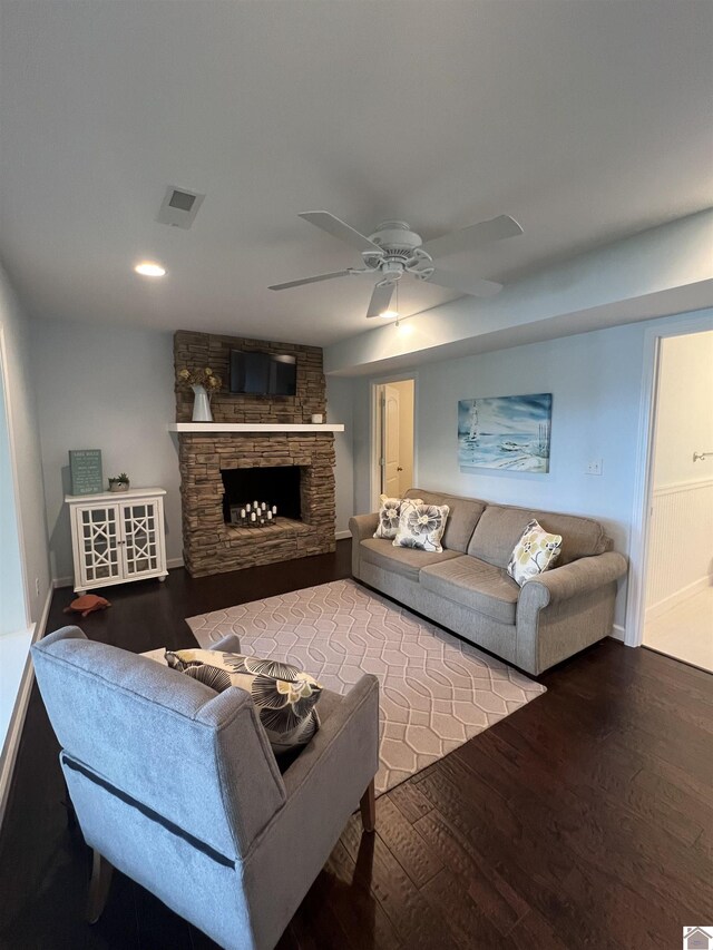 living room with ceiling fan, brick wall, a stone fireplace, and hardwood / wood-style flooring