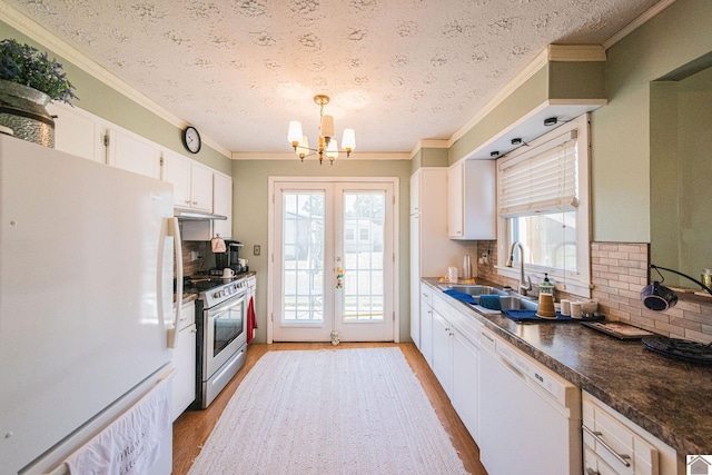 kitchen with white appliances, light wood-type flooring, an inviting chandelier, sink, and white cabinets