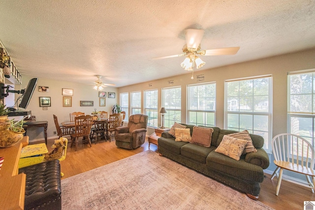 living room with ceiling fan, baseboards, a textured ceiling, and wood finished floors