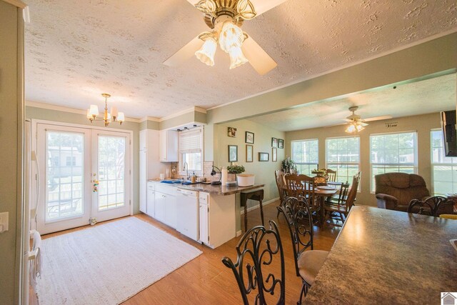 kitchen with ceiling fan with notable chandelier, a textured ceiling, white cabinets, dishwasher, and light hardwood / wood-style floors