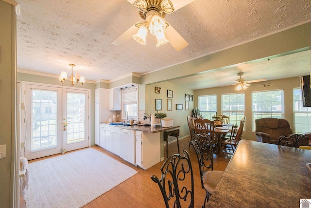 kitchen with light wood-style flooring, a sink, a textured ceiling, white cabinetry, and white dishwasher