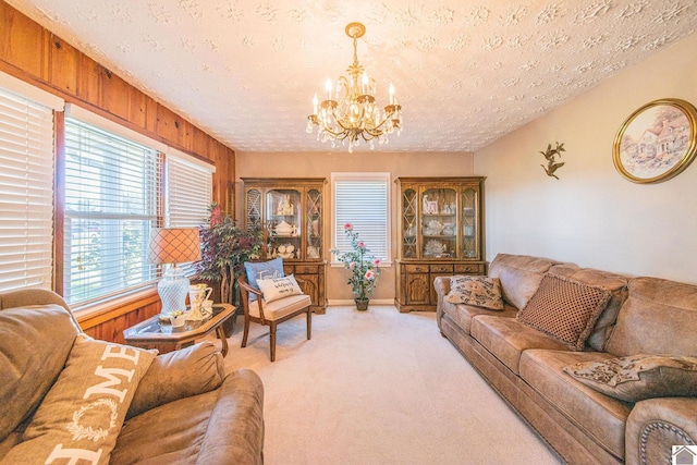 living room with wooden walls, a textured ceiling, a chandelier, and light carpet