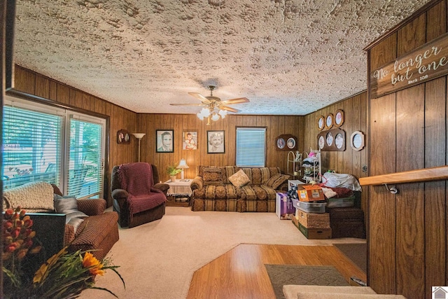 carpeted living area featuring wooden walls and a ceiling fan