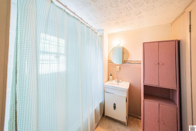 bathroom with a textured ceiling, shower / bath combination with curtain, and vanity