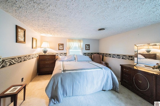 bedroom with a textured ceiling and light colored carpet