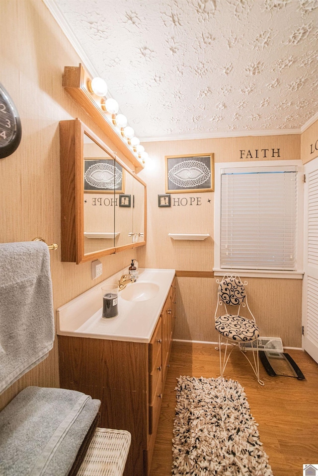 bathroom featuring vanity, wood-type flooring, a textured ceiling, and crown molding