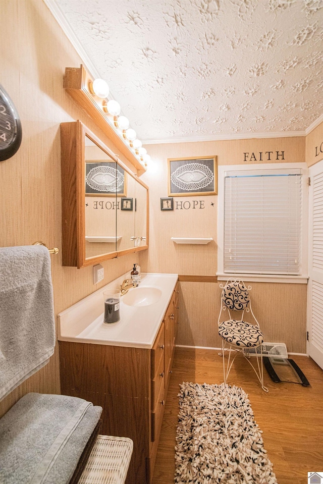 bathroom featuring a textured ceiling, vanity, wood finished floors, and ornamental molding