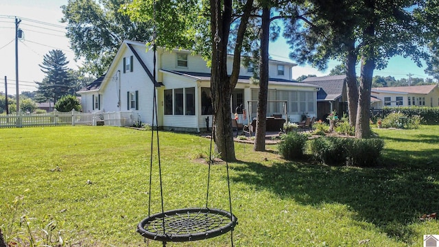 back of house featuring fence, a yard, and a sunroom