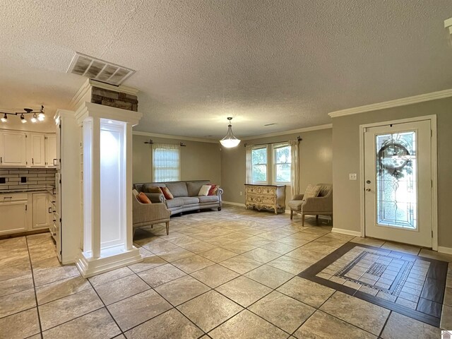 tiled foyer entrance featuring a textured ceiling, ornate columns, crown molding, and track lighting