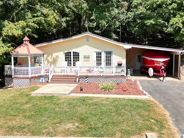 ranch-style home with a carport, a deck, and a front yard