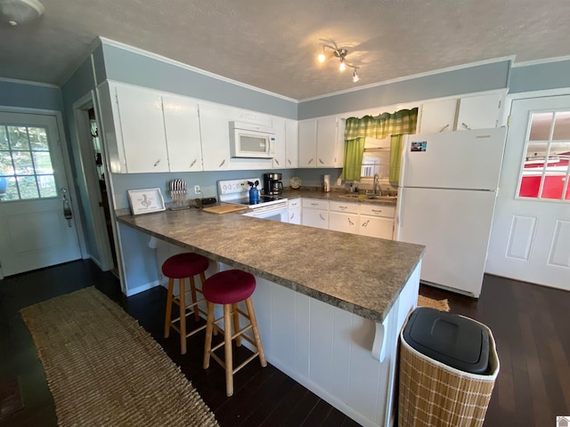 kitchen featuring crown molding, white appliances, white cabinetry, dark hardwood / wood-style floors, and a kitchen bar