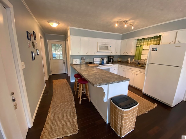 kitchen with white appliances, dark hardwood / wood-style flooring, white cabinetry, kitchen peninsula, and a kitchen breakfast bar