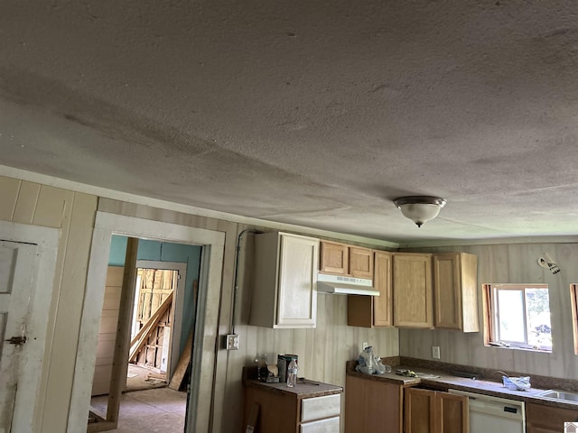 kitchen with dishwasher, dark countertops, a textured ceiling, wood walls, and under cabinet range hood