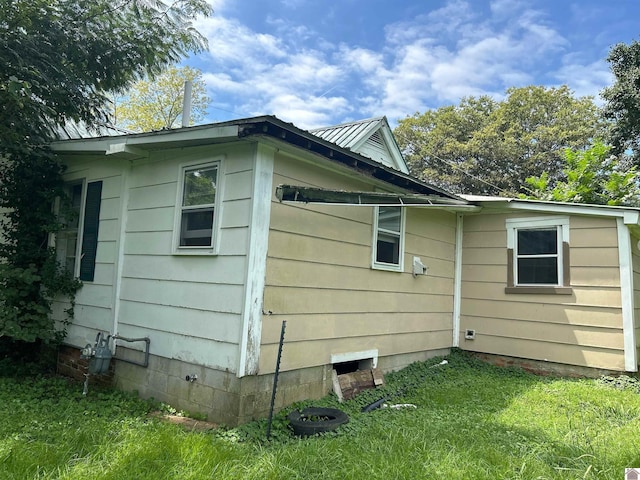 view of property exterior with metal roof and a lawn