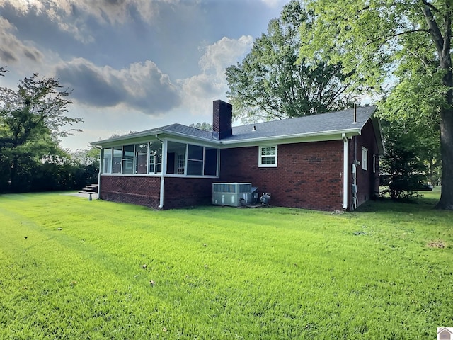 back of house featuring cooling unit, a sunroom, and a yard