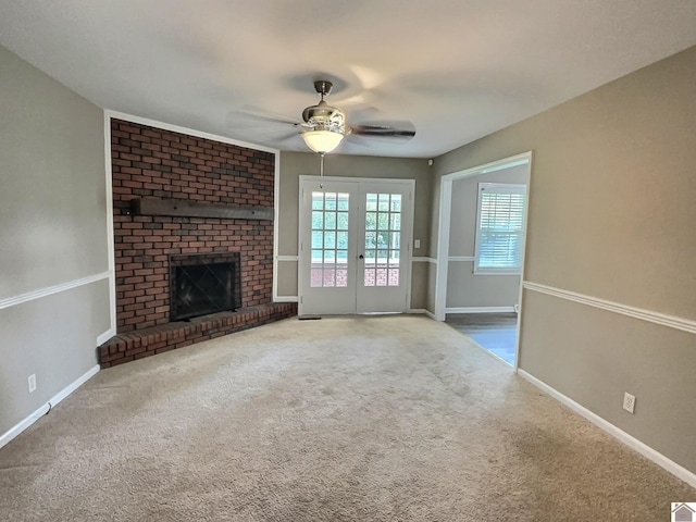 unfurnished living room featuring ceiling fan, a fireplace, carpet, and french doors