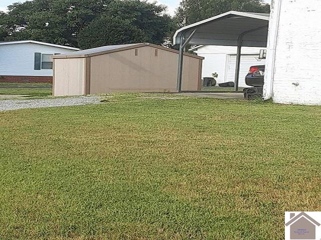 view of yard featuring a carport and an outbuilding