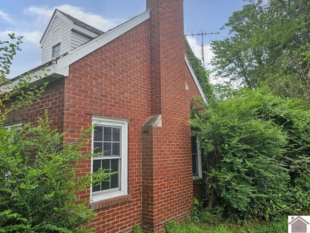 view of side of home with a chimney and brick siding