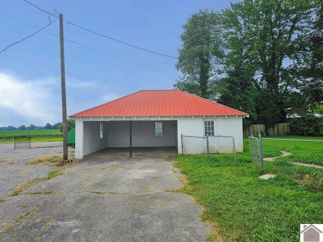 view of outdoor structure featuring fence, aphalt driveway, and a carport