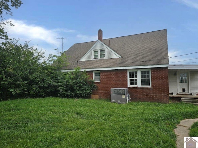 rear view of property featuring brick siding, a lawn, a chimney, and central AC unit