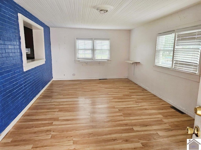 empty room with light wood-style floors, visible vents, and baseboards