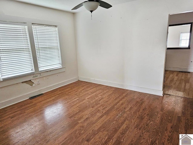 spare room featuring visible vents, ceiling fan, baseboards, and wood finished floors