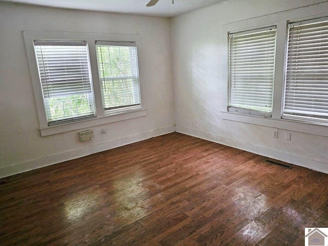 unfurnished room featuring dark wood-style floors, ceiling fan, visible vents, and baseboards