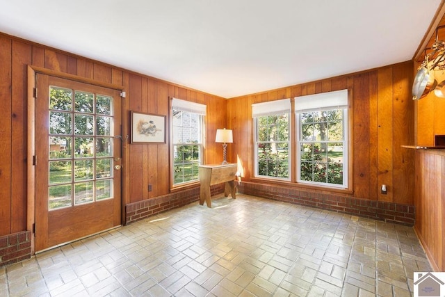 interior space featuring plenty of natural light, brick floor, and wooden walls