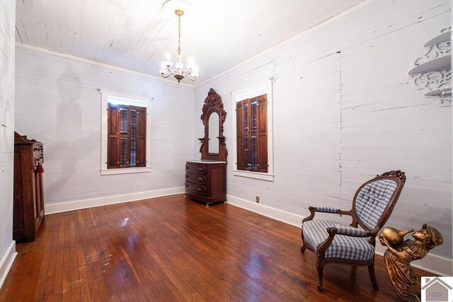 living area with baseboards, an inviting chandelier, and dark wood finished floors