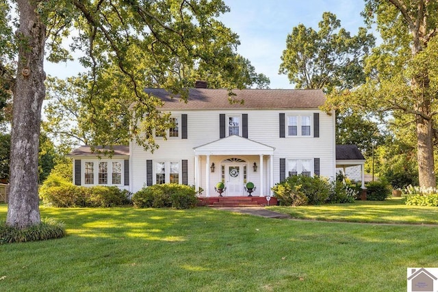 colonial inspired home with a chimney and a front yard