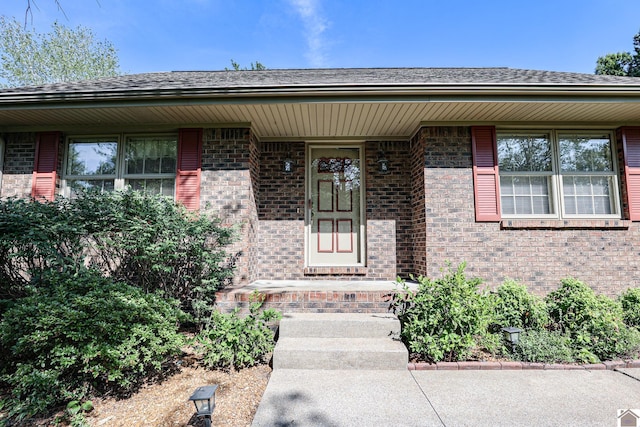 property entrance featuring brick siding and roof with shingles