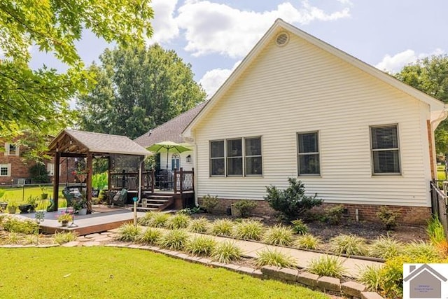 rear view of property with a wooden deck, a gazebo, and a yard