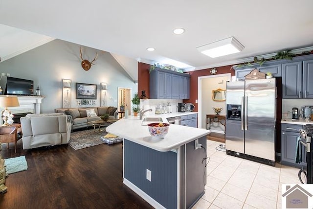 kitchen with ornamental molding, light tile patterned flooring, sink, lofted ceiling, and stainless steel appliances