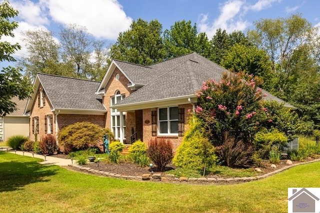 view of front of house featuring brick siding, a front lawn, and roof with shingles