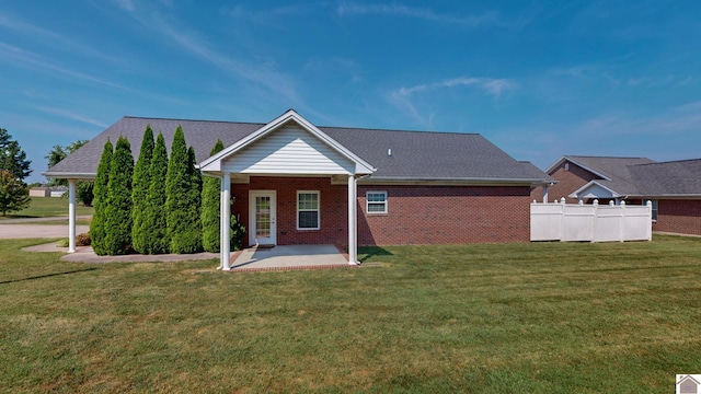 rear view of house featuring a lawn and a patio