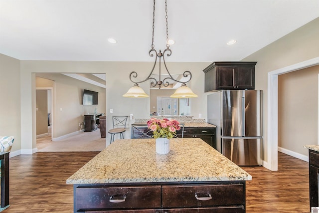 kitchen with a kitchen island, dark brown cabinetry, dark hardwood / wood-style floors, and stainless steel refrigerator