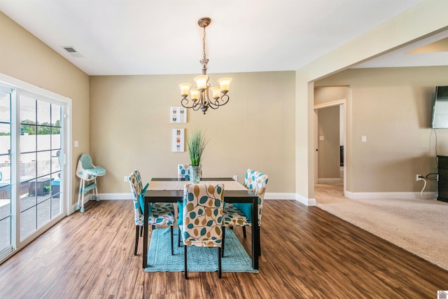 dining area with hardwood / wood-style flooring and an inviting chandelier