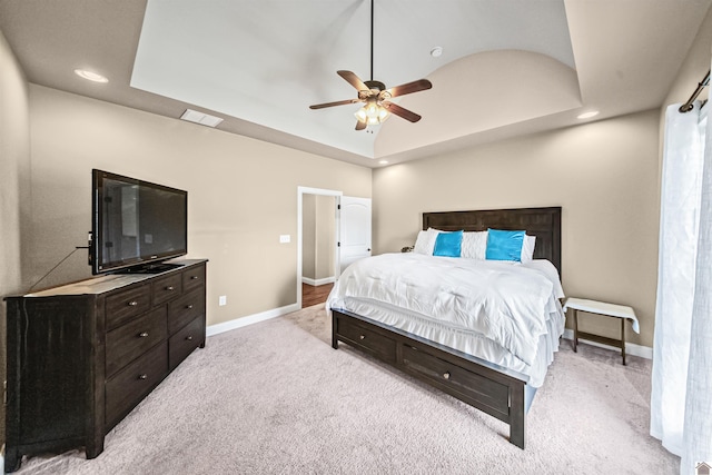 bedroom featuring ceiling fan, light carpet, and a tray ceiling