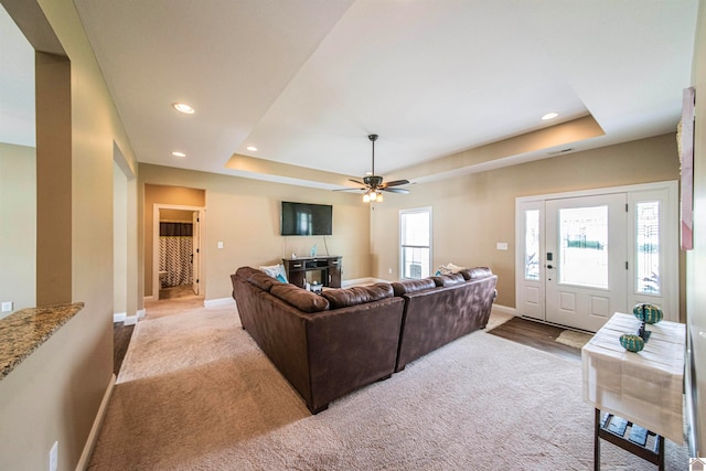 living room featuring ceiling fan, a raised ceiling, and carpet