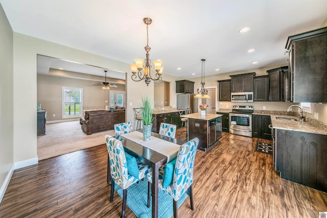 dining area with carpet, sink, and ceiling fan with notable chandelier