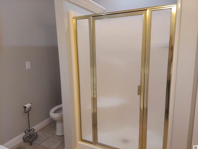 bathroom with tile patterned flooring, toilet, and a shower with door