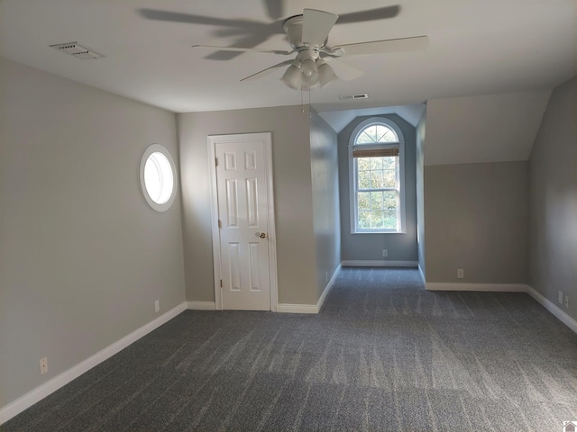 spare room with lofted ceiling, dark carpet, and ceiling fan