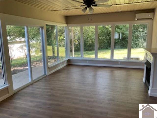 unfurnished sunroom with wooden ceiling, a fireplace, a wall mounted AC, and ceiling fan