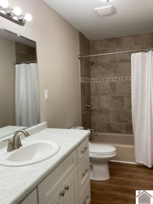 full bathroom with vanity, toilet, hardwood / wood-style flooring, and shower / tub combo with curtain